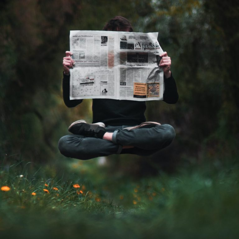Photo d'un homme en lévitation lisant la presse dans la nature